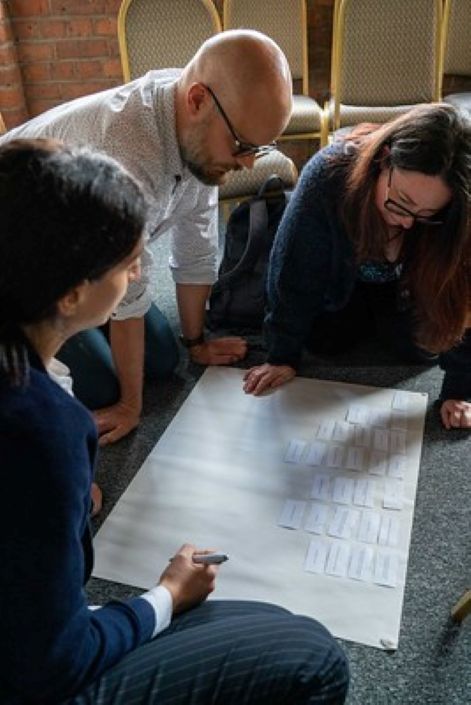 Small 705 VitaeCon2023 A group of people gather around a large sheet of paper brainstorming and discussing in a workshop.