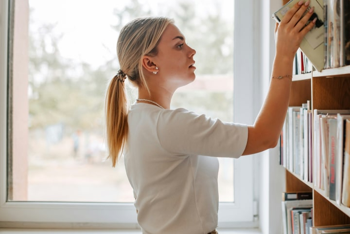 women-picking-book-off-shelve women-picking-book-off-shelve